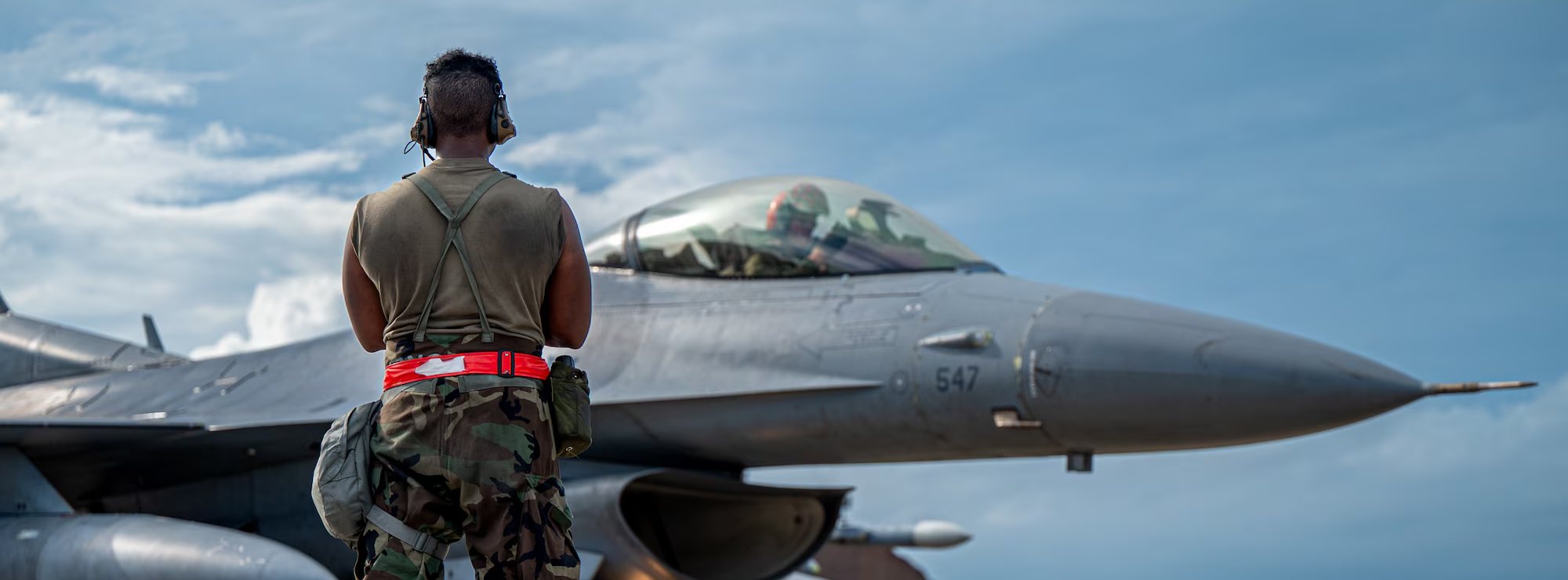 A fighter jet on the flightline with its crew chief standing by