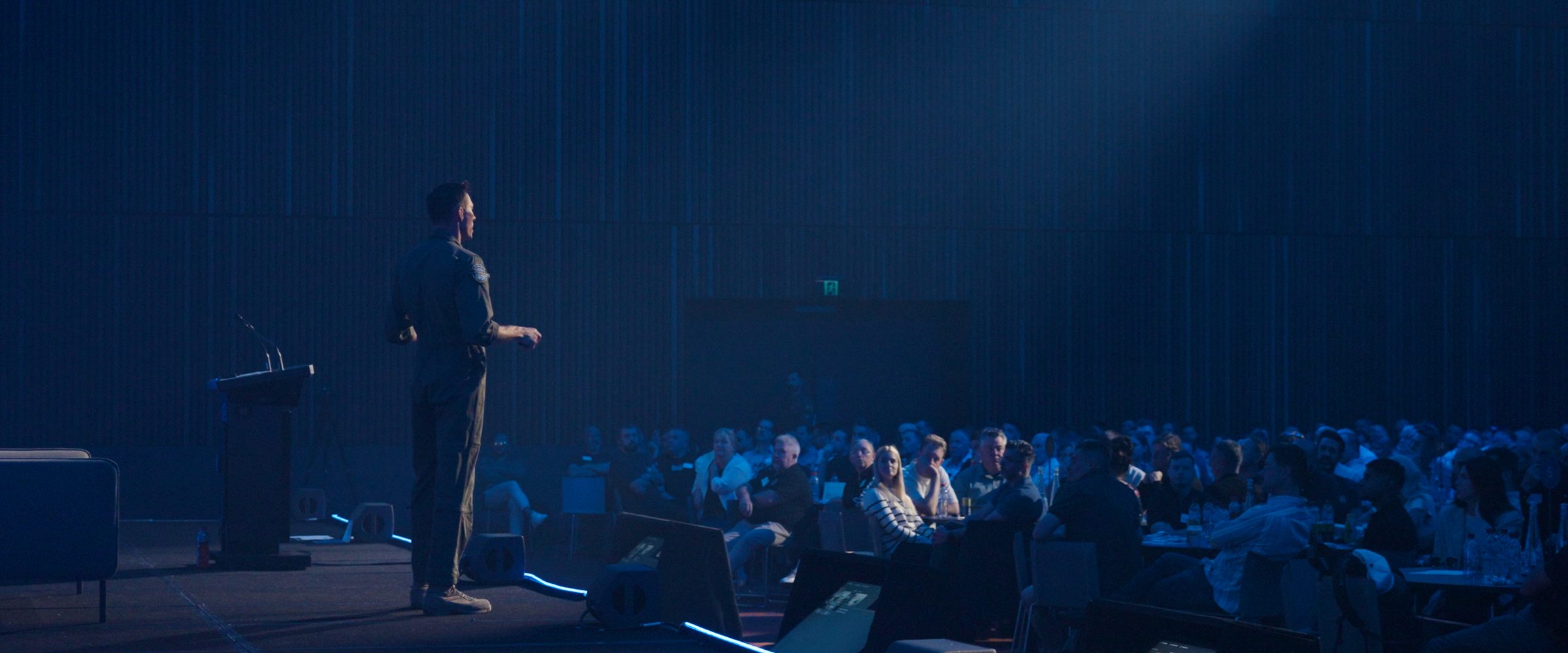 An Afterburner pilot on stage in front of a seated audience