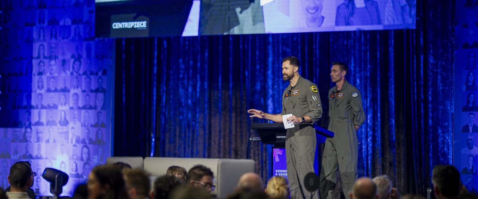Two Afterburner pilots on stage in front of a seated audience