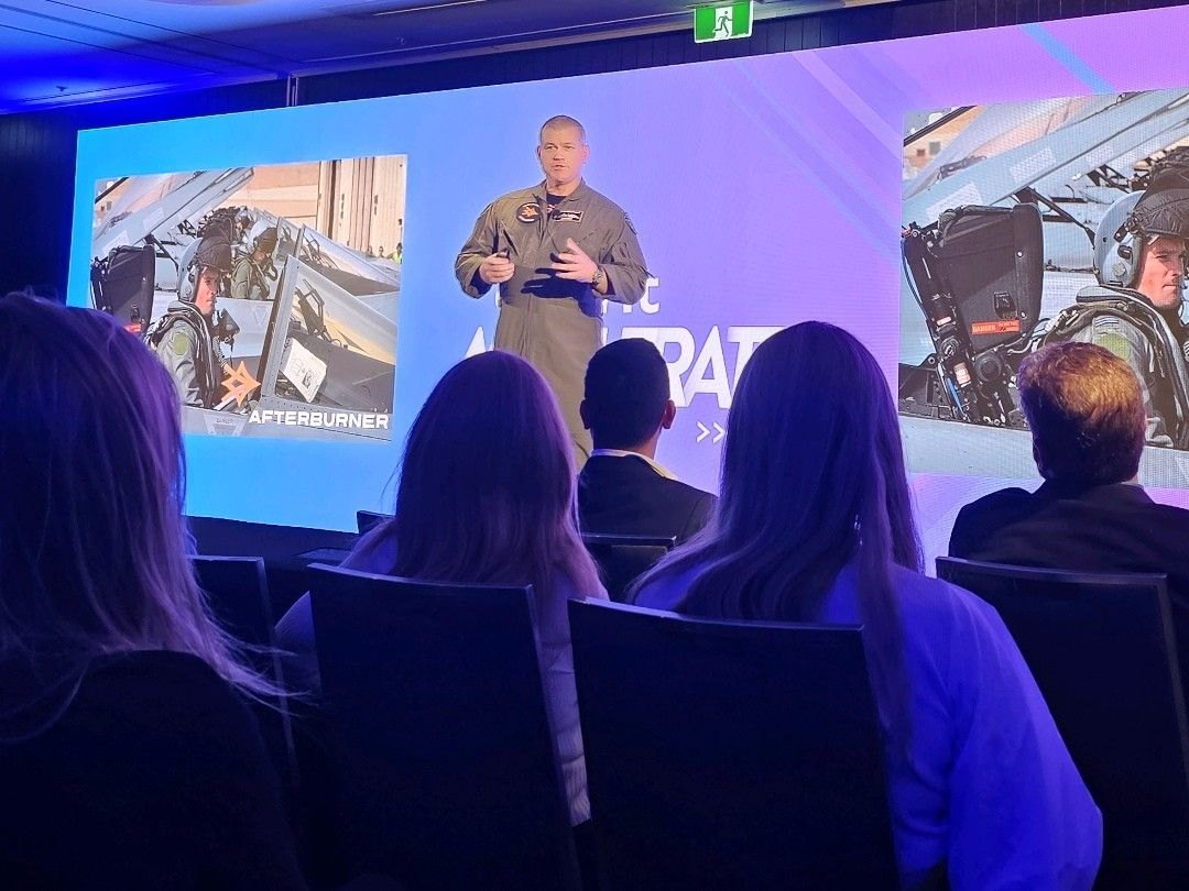 An Afterburner fighter pilot presenting to a seated corporate audience