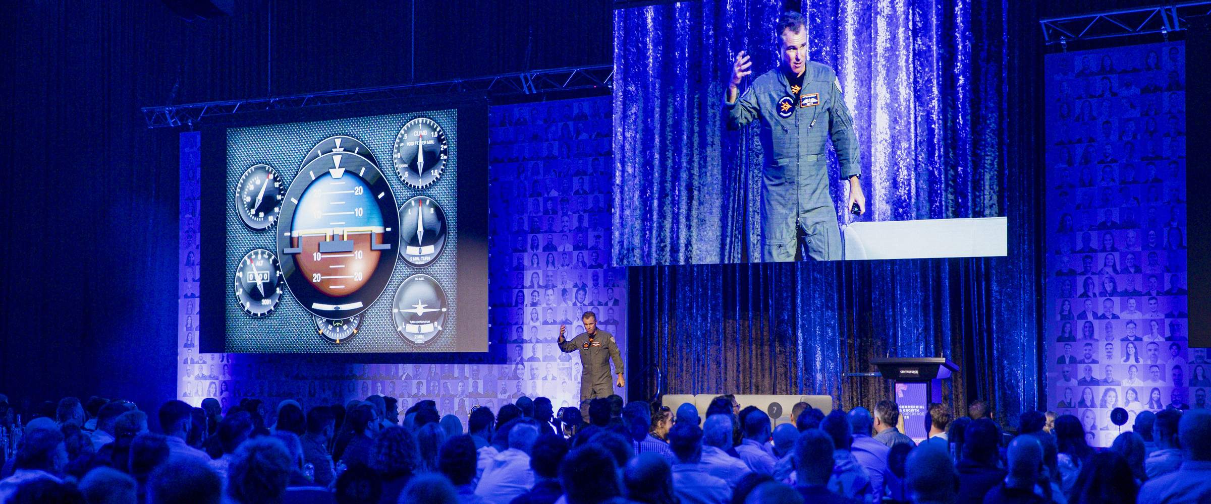 An Afterburner fighter pilot on stage in front of a full conference room